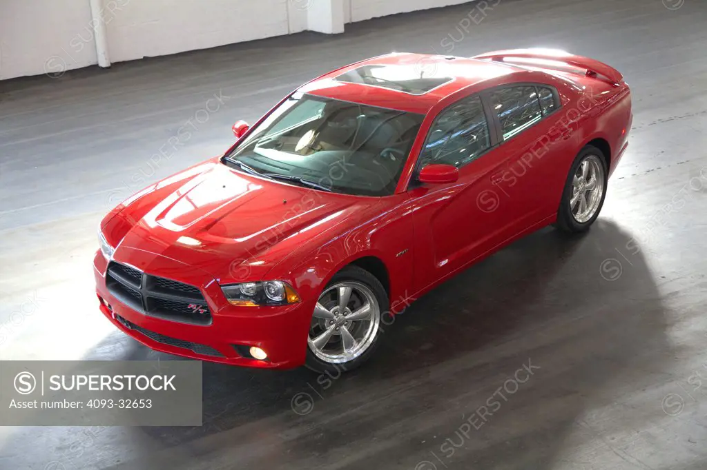 Overhead front 3/4 static view of a red 2012 Dodge Charger R/T HEMI parked inside a warehouse.