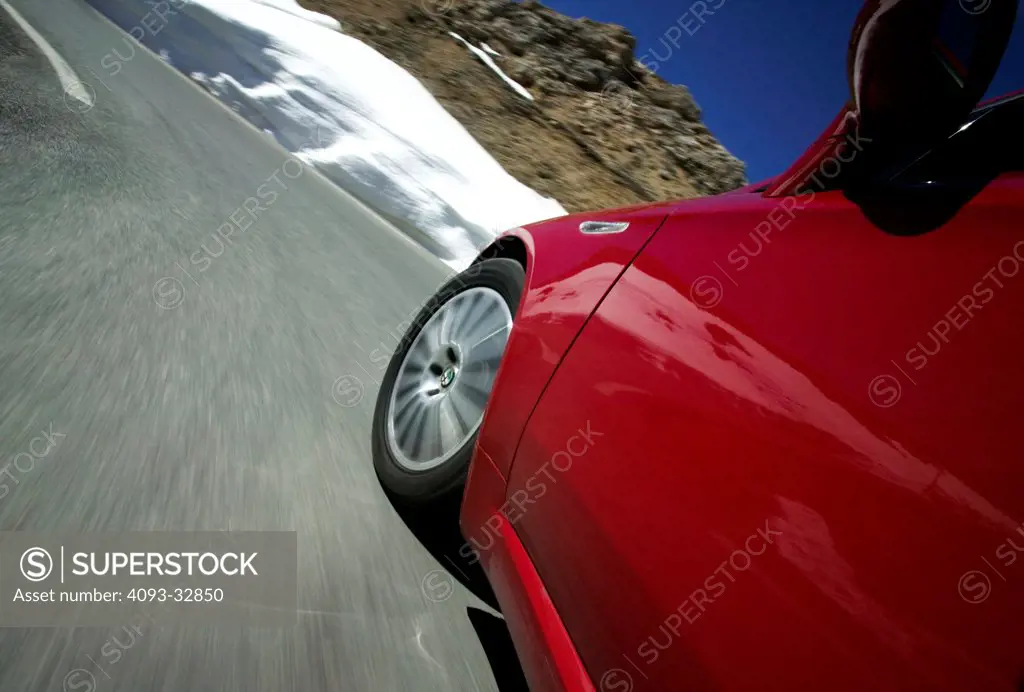 2007 Alfa Romeo spider driving on mountain pass, close-up on side and front wheel