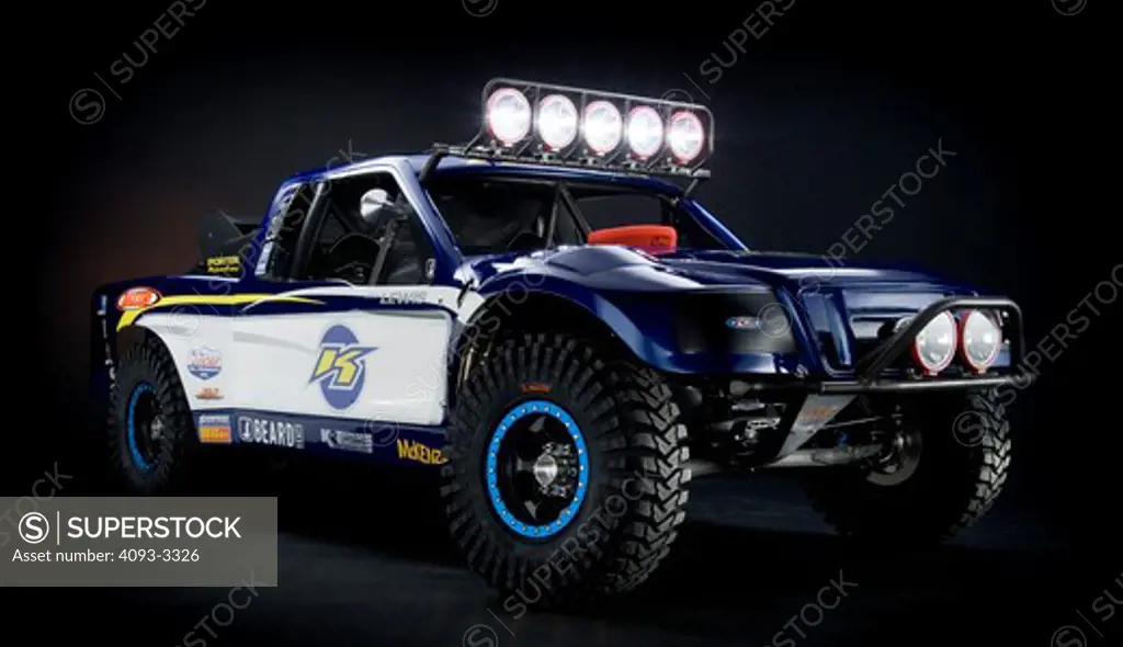 Desert Race truck with lights on and sponsor stickers all over shot in the studio.