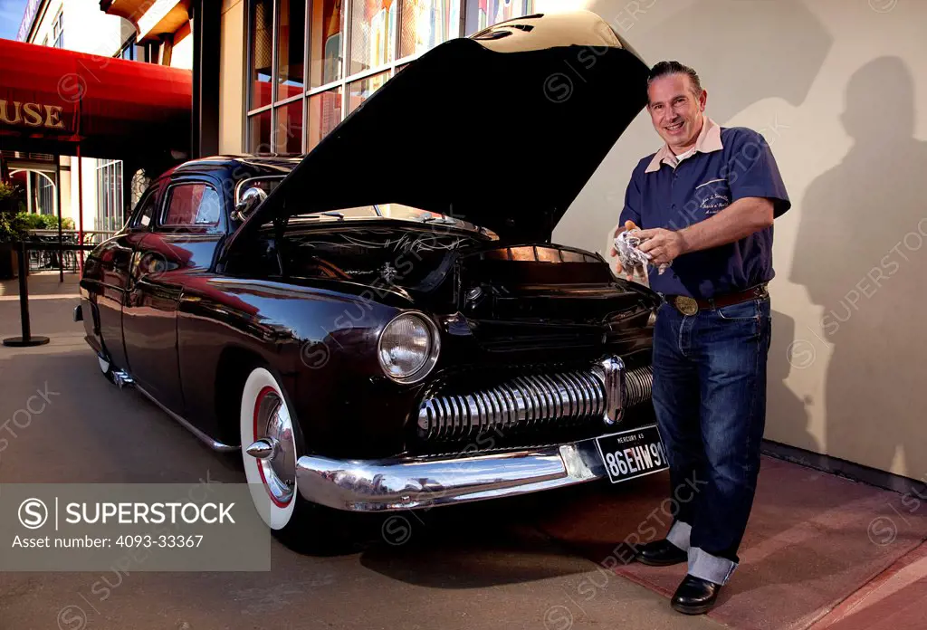 Car owner poses and checks oil of 1949 Mercury Flathead V8 custom coupe.