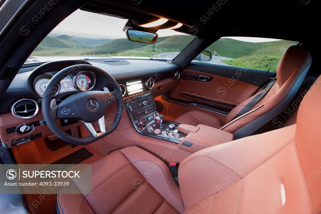 Interior view of a 2011 Mercedes-Benz SLS AMG showing the steering wheel, instrument panel, center console, dashboard and leather seats.