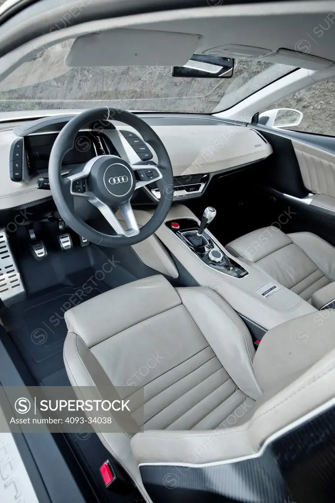 Interior view of the 2010 Audi Sport Quattro Concept showing the steering wheel, instrument panel, center console, gear shift lever and tan leather seats.