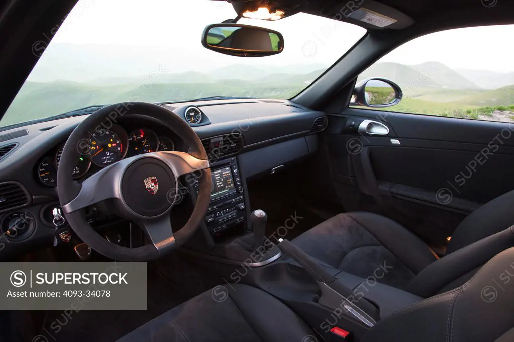 Interior of a 2012 Porsche 911 GT3 showing the steering wheel, instrument panel, center console with navigation multi function display and gear shift lever.