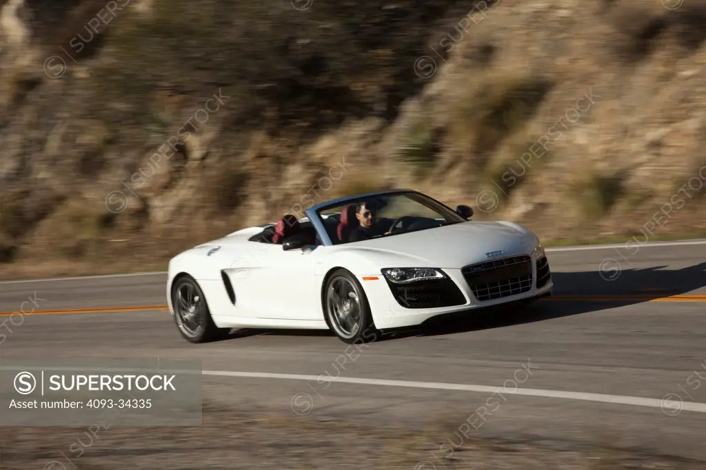 Front 3/4 action of a white 2011 Audi R8 Spyder convertible on a rural mountain road.