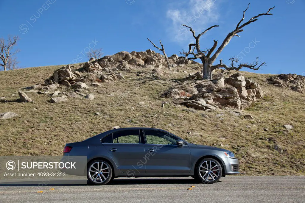 Static profile view of a silver 2012 Volkswagen Jetta GLI parked on a rural mountain road.