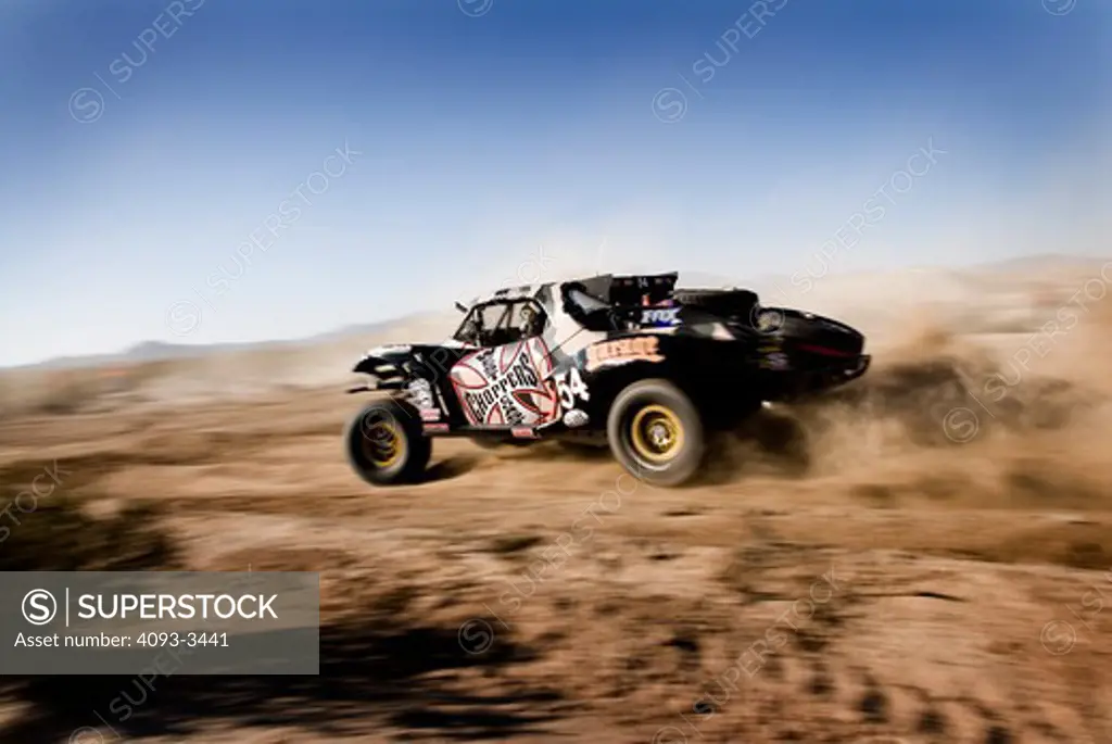Baja desert race trucks spinning and kicking up dirt and dust.