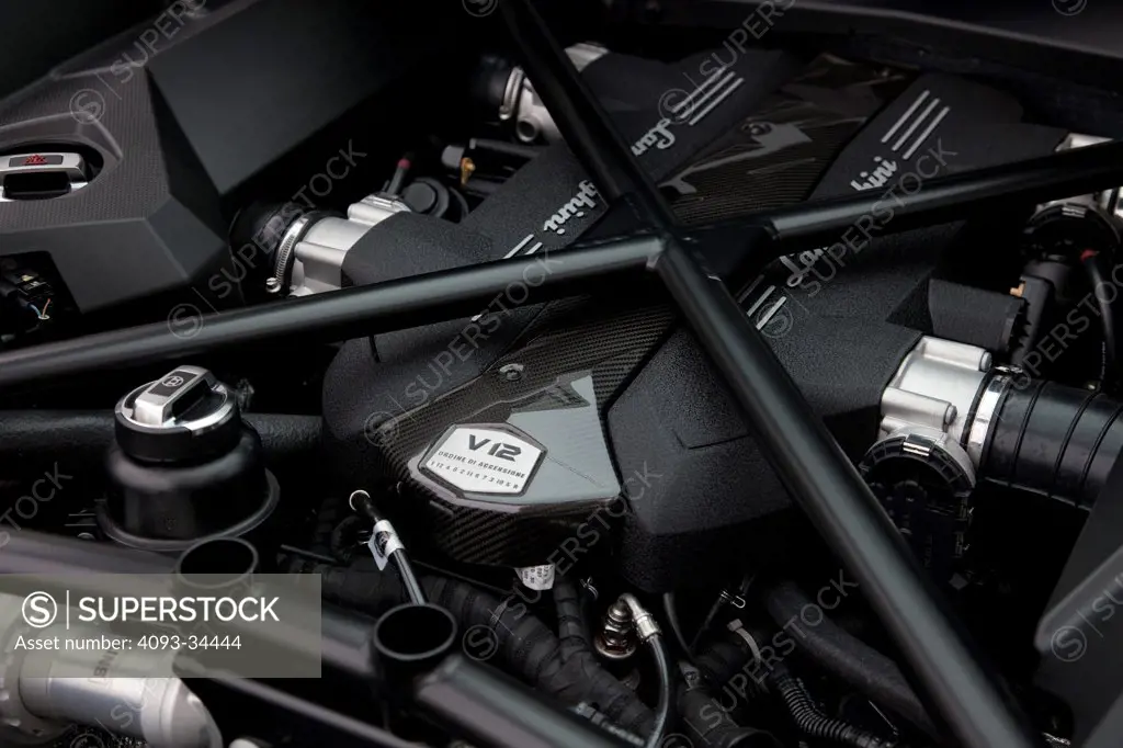 Interior view of a satin black 2012 Lamborghini Aventador showing the 4.5 liter V12 engine.