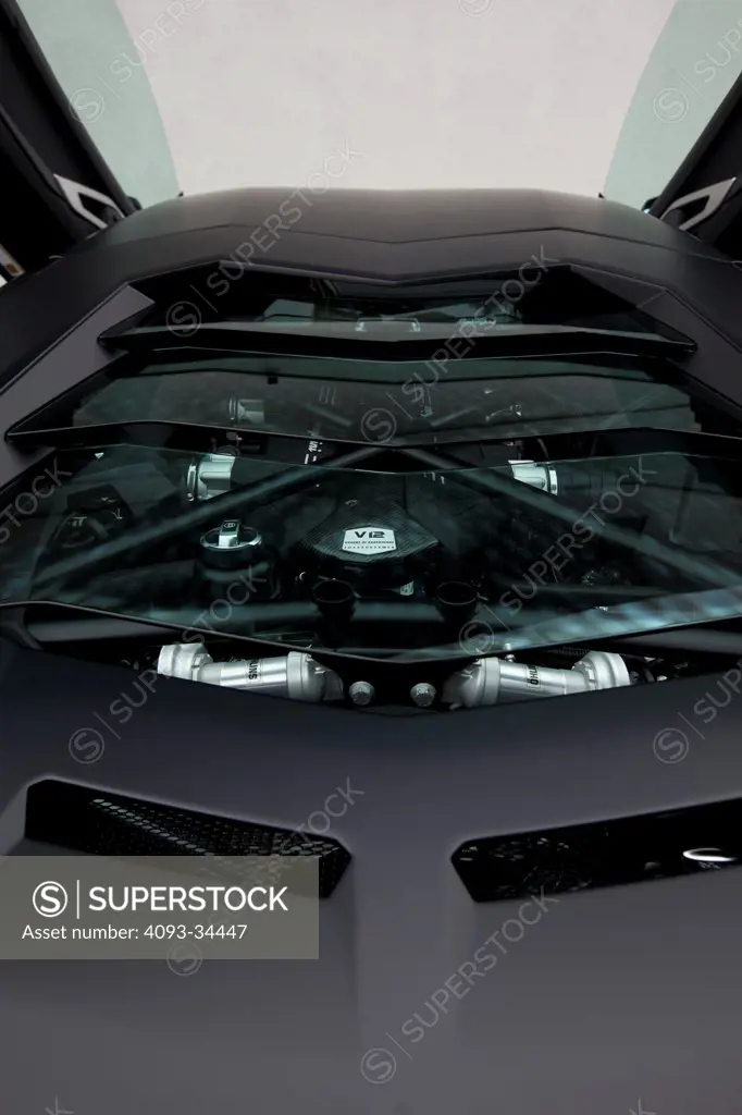 Exterior detail view of a satin black 2012 Lamborghini Aventador showing the glass engine cover and the V12 engine.