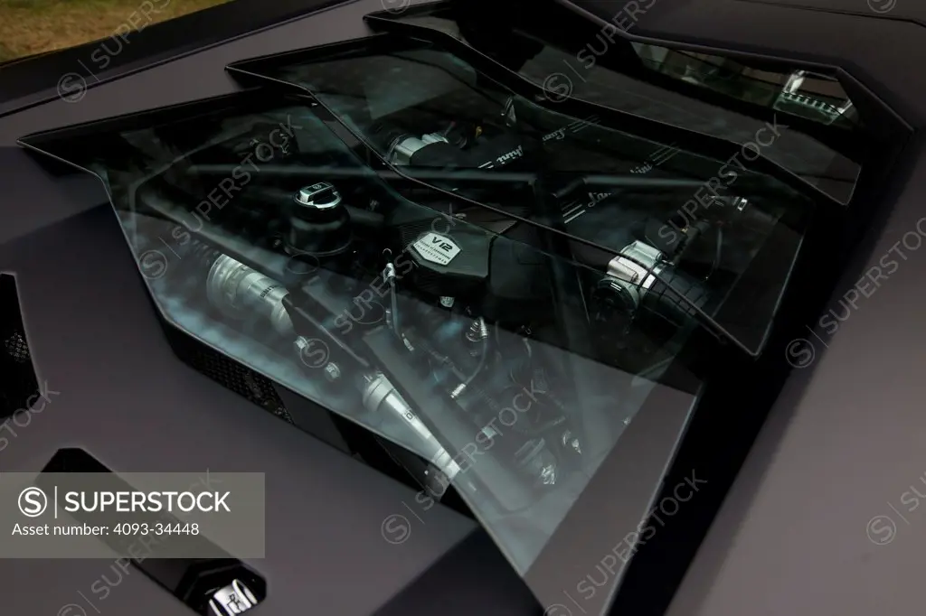 Exterior detail view of a satin black 2012 Lamborghini Aventador showing the glass engine cover and the V12 engine.