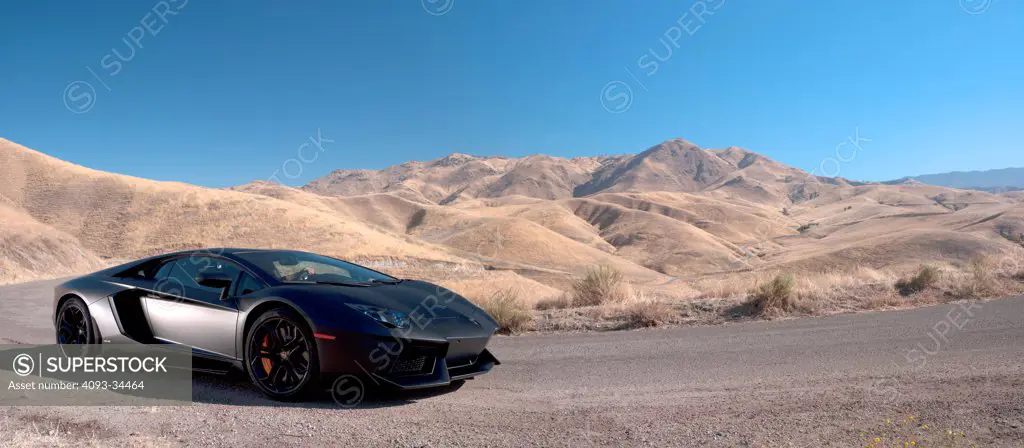 Front 3/4 static panorama of a satin black 2012 Lamborghini Aventador on a rural mountain road.