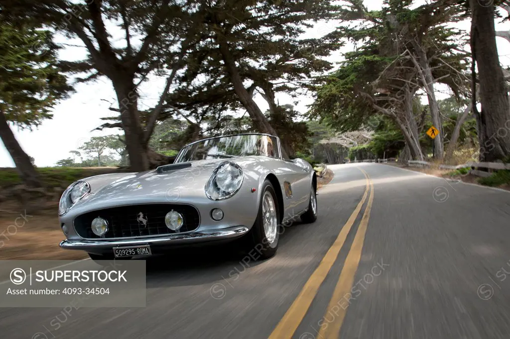 Front 3/4 action of a silver 1957 Ferrari 250 GT California Spider LWB on a rural road near Monterey, California.