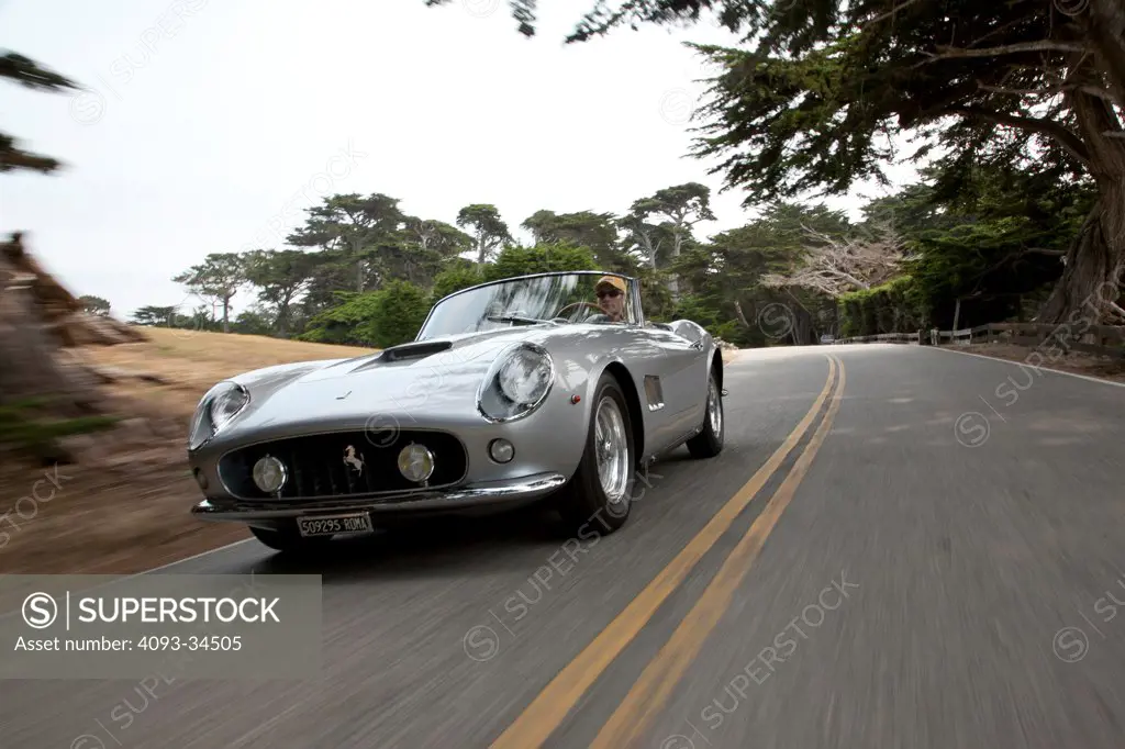 Front 3/4 action of a silver 1957 Ferrari 250 GT California Spider LWB on a rural road near Monterey, California.