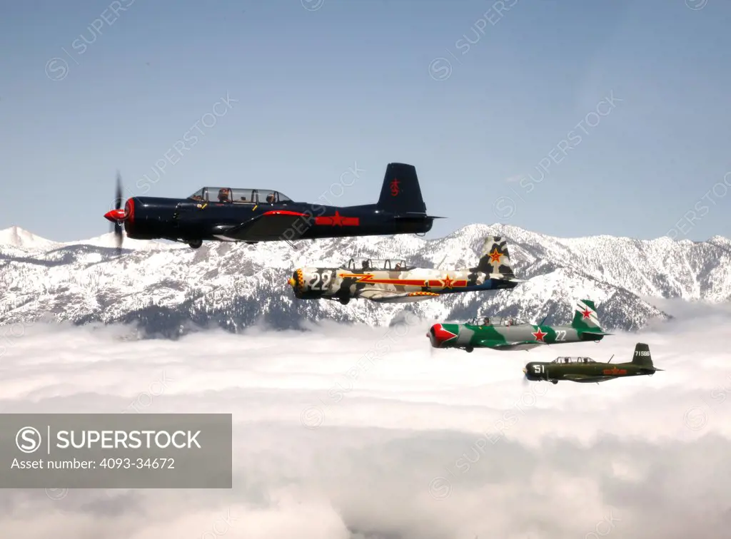 Group of 1960 Nanchang China CJ-6 aerobatic trainer aircraft flying over mountains in California.