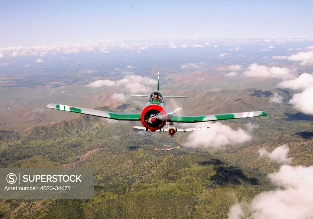 Group of 1960 Nanchang China CJ-6 aerobatic trainer aircraft flying over mountains in California. Straight on nose view.