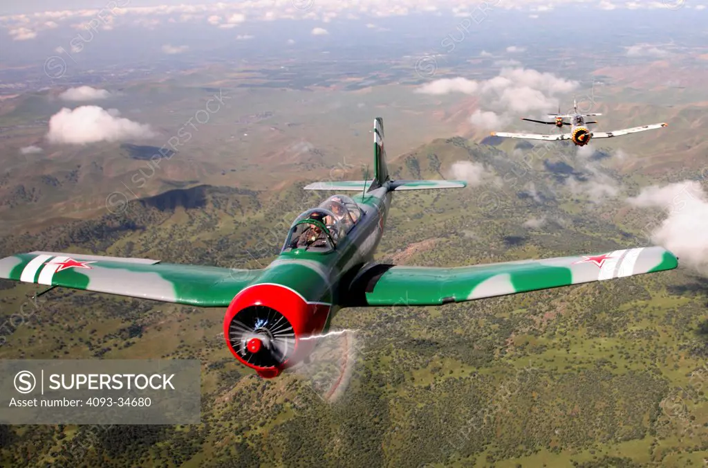 Group of 1960 Nanchang China CJ-6 aerobatic trainer aircraft flying over mountains in California.