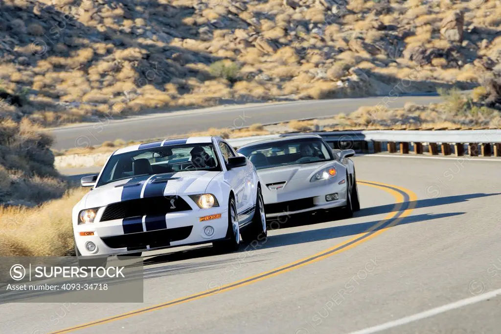 Action of 2010 Ford Shelby GT 500 and Corvette Z06 on a rural mountain road.
