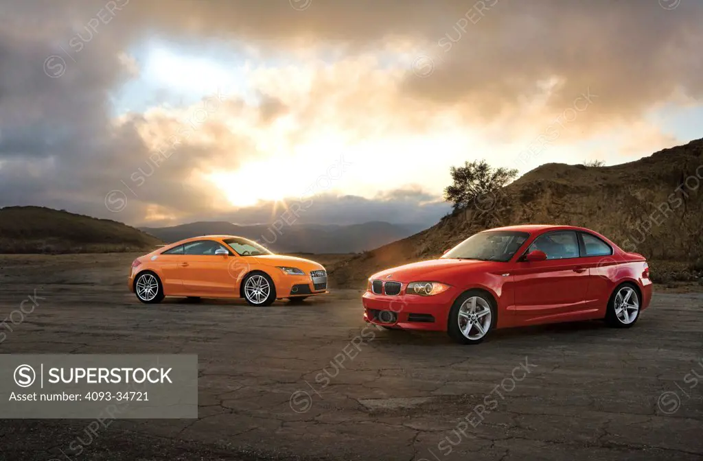 Static group image of the 2010 Audi TTS and BMW 135i parked in a rural location. 