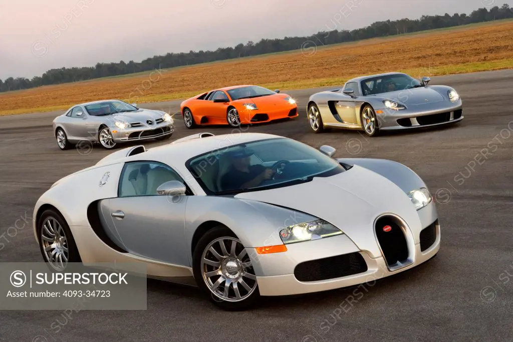 Group view of a Bugatti Veyron , McLaren Mercedes SLR, Lamborghini LP640 and Porsche Carrera GT parked on a race track.