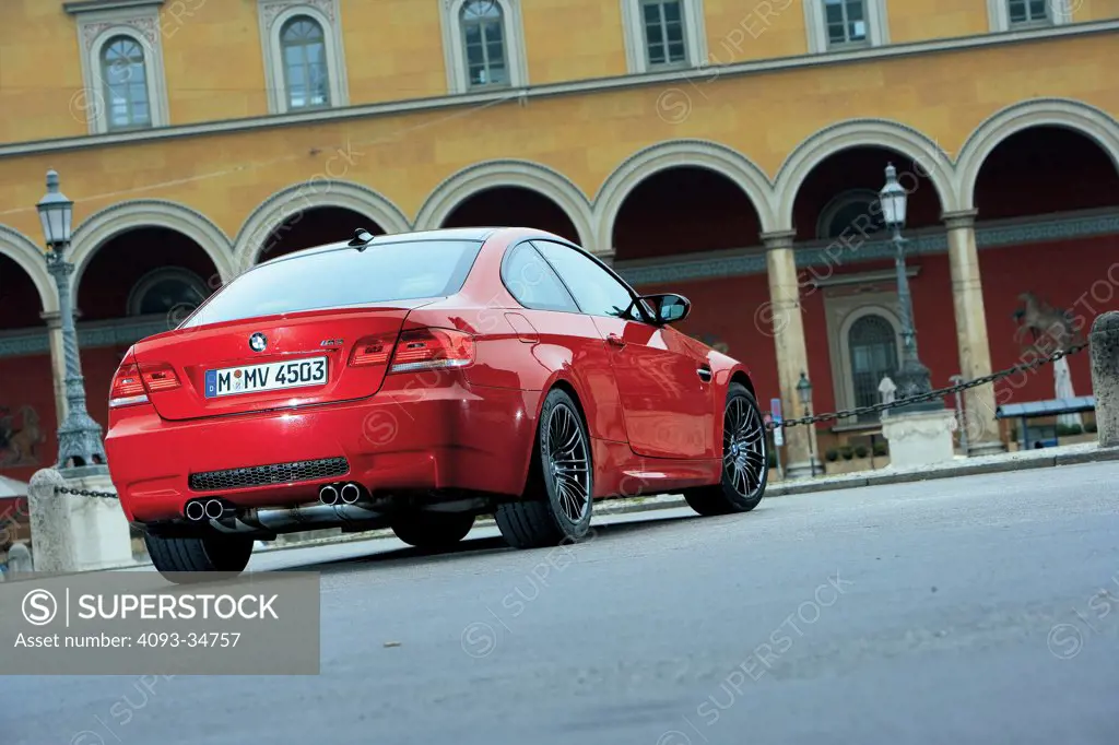 Rear 3/4 static view of a red 2008 BMW M3 parked in a city in Germany.