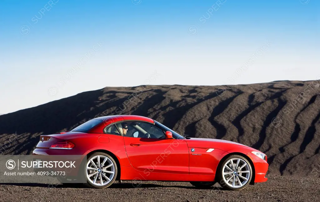 Rear 3/4 static view of a 2010 BMW Z4 Roadster parked on a hill of coal.