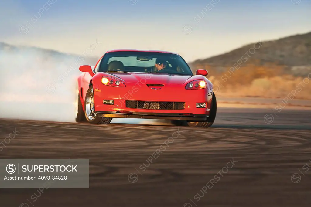 Front nose drifting action of a red 2010 Chevrolet Corvette Grand Sport. Burnout smoke.