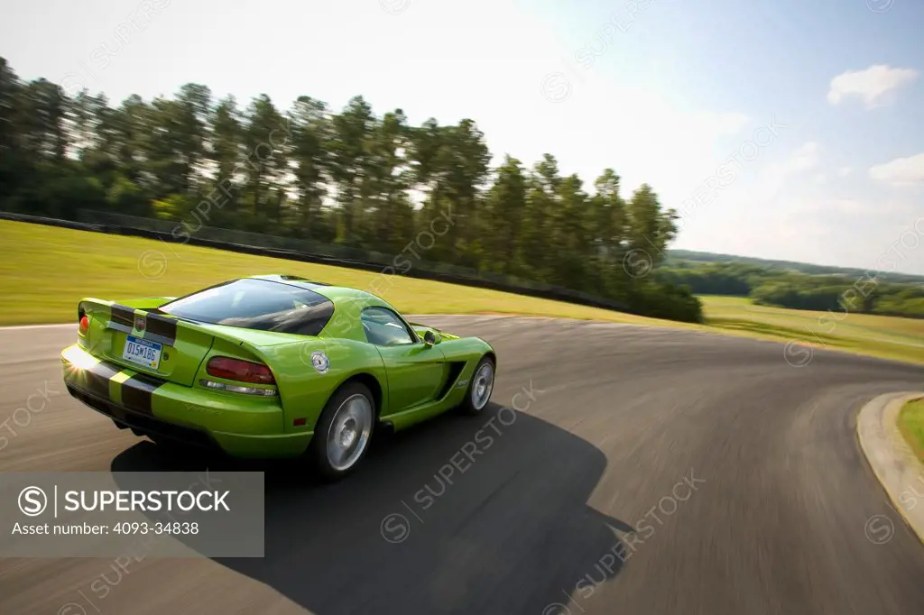 Rear 3/4 action view of a green 2010 Dodge Viper SRT10 racing around a track.