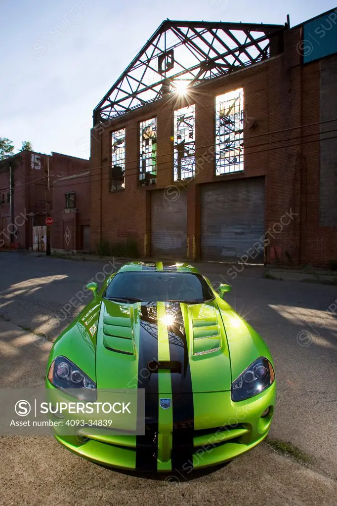 Straight on static nose view of a green 2010 Dodge Viper SRT10 in front of an abandoned building.