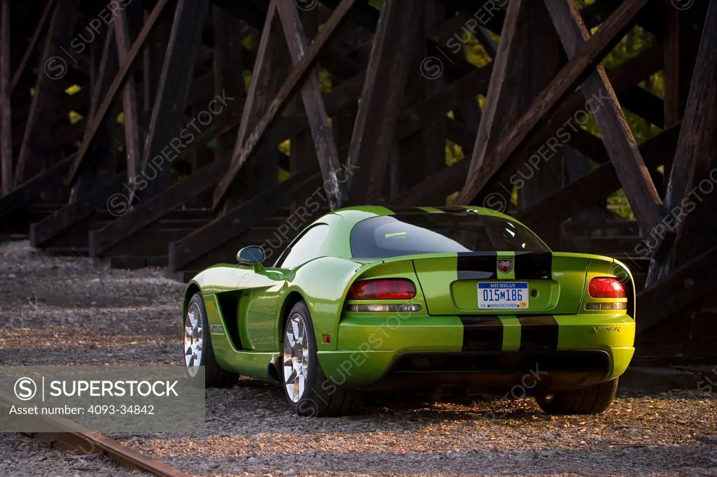 Rear 3/4 static view of a green 2010 Dodge Viper SRT10 under an old wooden railroad trestle.