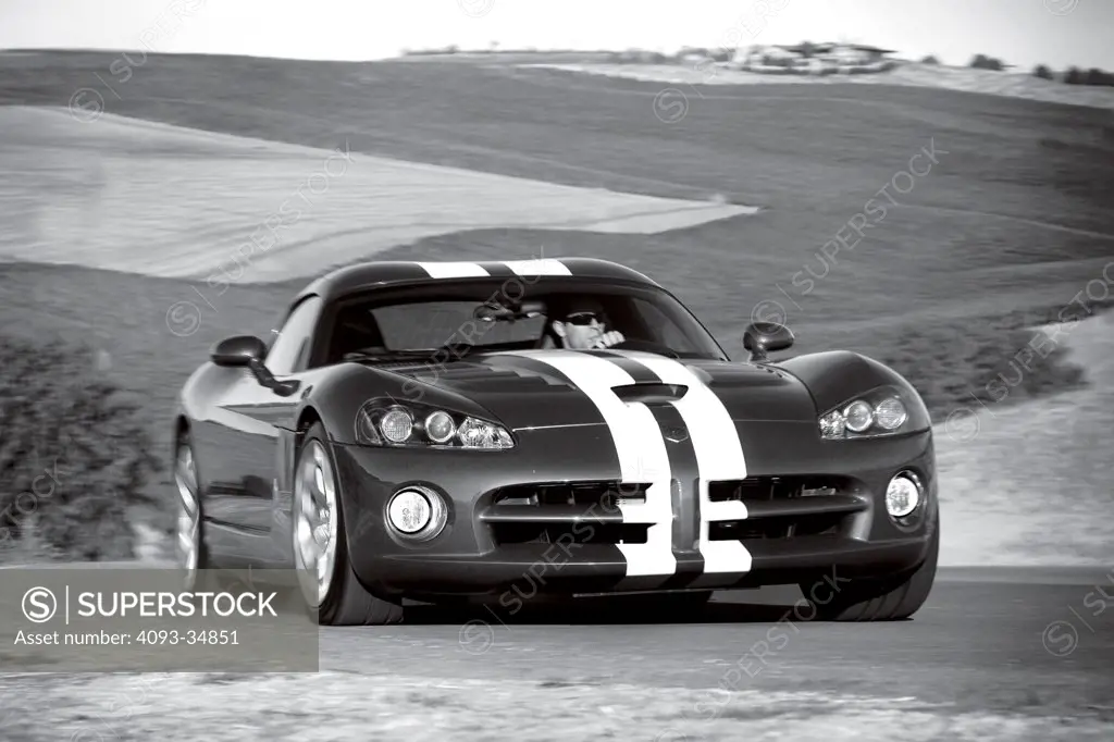 Front 3/4 action view of a 2010 Dodge Viper SRT10 racing around a track. Black & White.