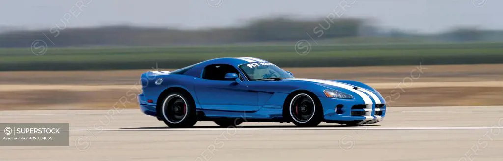 Profile action view of a blue 2010 Hennessey Dodge Viper SRT10 on a rural road.