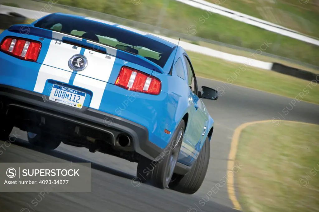 Rear 3/4 drifting action of a blue 2010 Ford Mustang GT.
