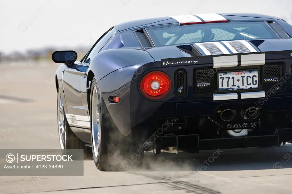Rear 3/4 action view of a Hennessey Ford GT1000 doing a burnout with smoke on a race track.