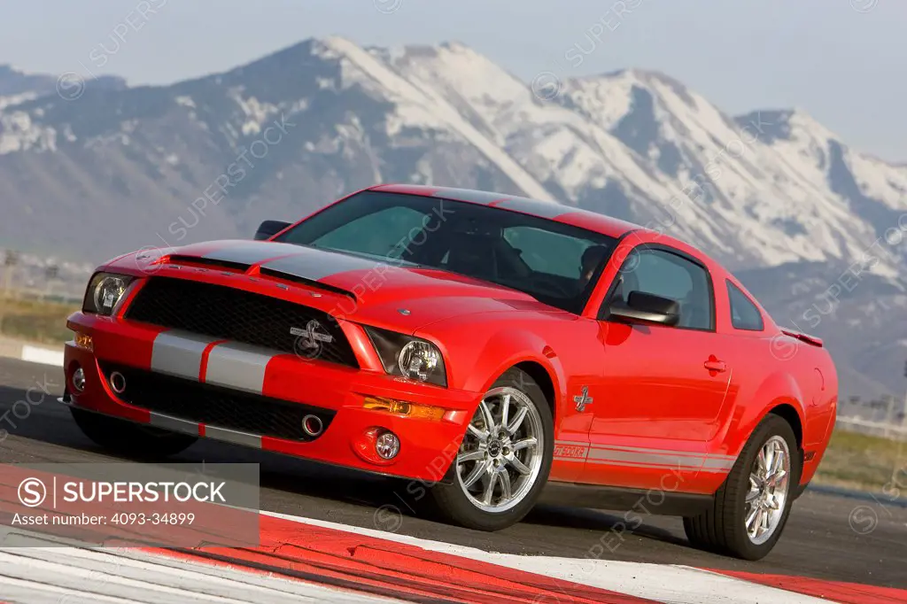 Front 3/4 static view of a red 2010 Ford Shelby GT500KR on a rural mountain race track.