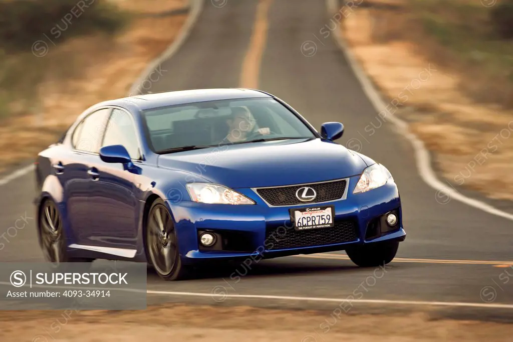 Front 3/4 action view of a blue 2010 Lexus IS-F on a rural road.