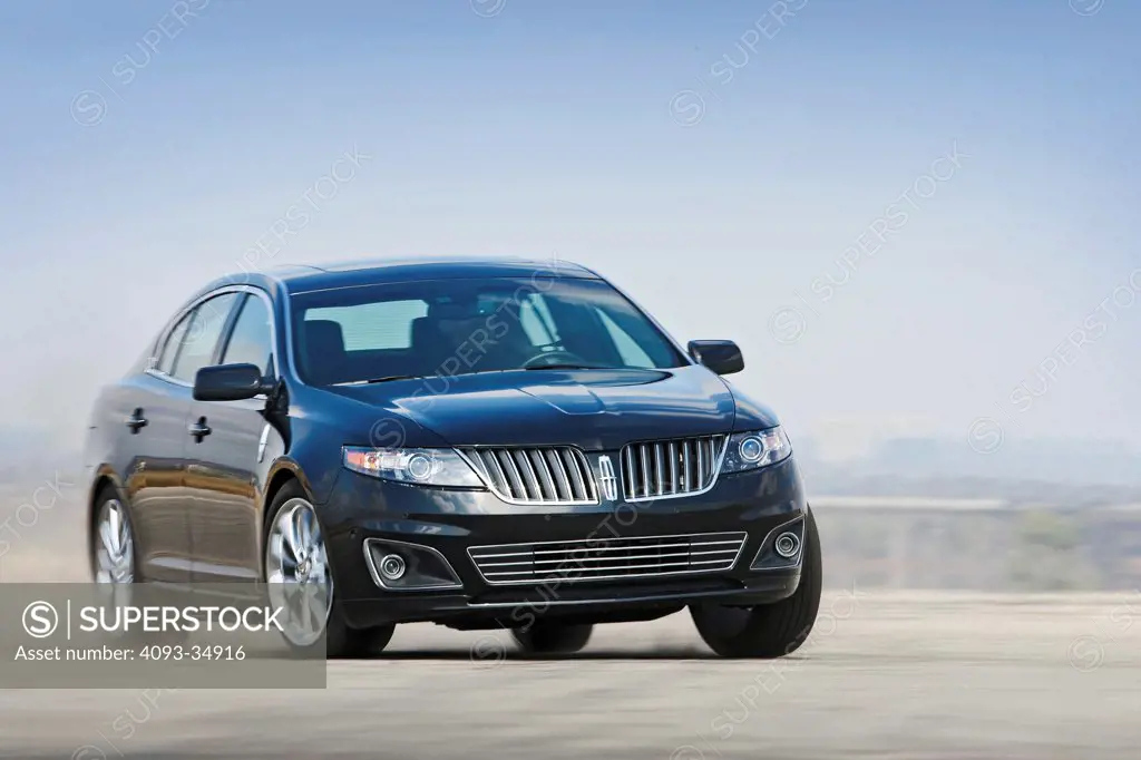 Front 3/4 action view of a black 2010 Lincoln MKS on a race track. 