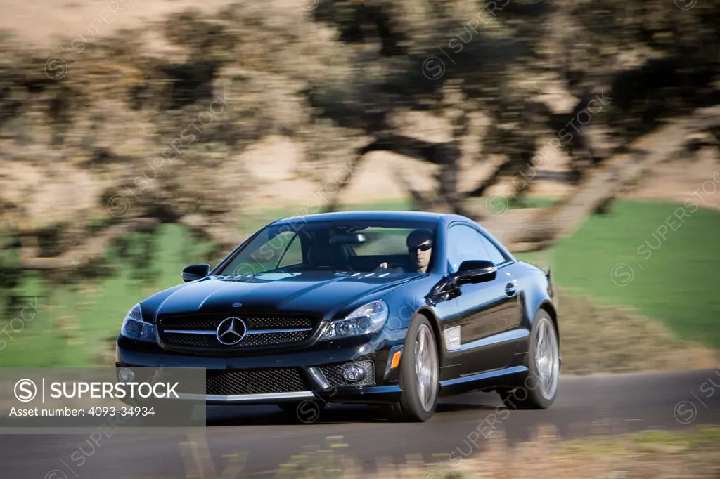 Front 3/4 action view of a black 2010 Mercedes-benz SL65 AMG driving on a rural mountain road.