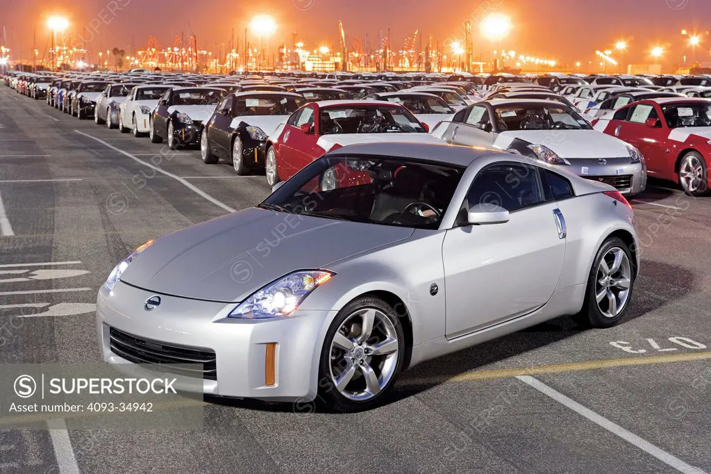 Front 3/4 static view of a silver 2008 Nissan 350Z in a loading yard with hundreds of other Nissan 350Z's at dusk.