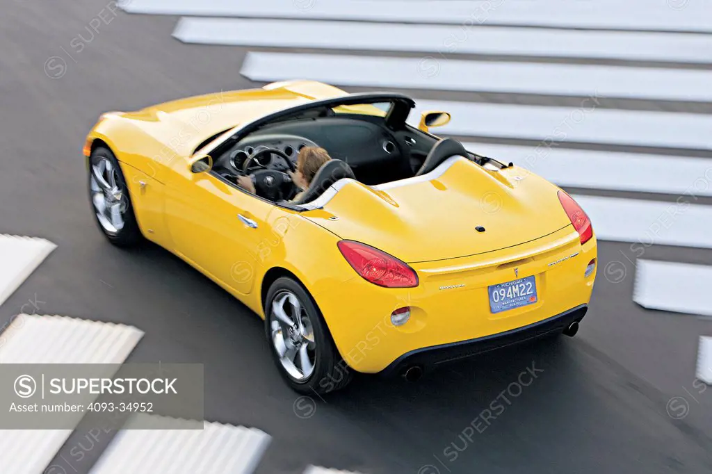High overhead rear 3/4 action view of a yellow 2010 Pontiac Solstice GXP.