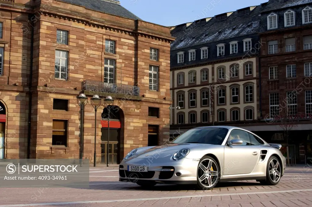 Front 3/4 static view of a silver 2010 Porsche 911 ( 997 series ) Turbo in a German village.