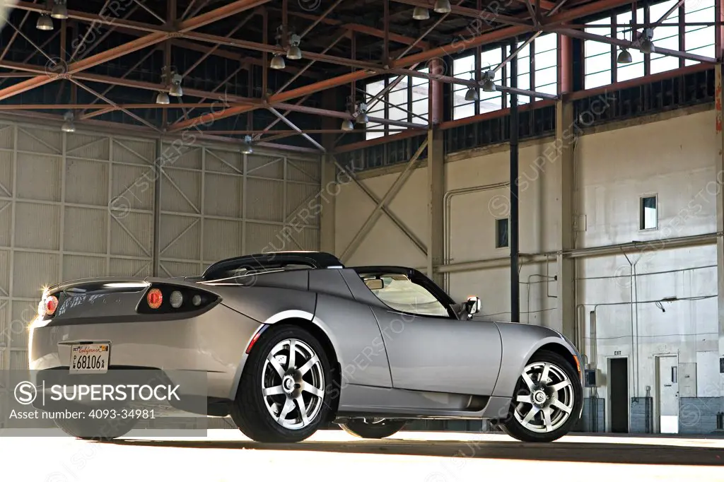 Rear 3/4 static view of a 2010 Tesla Roadster electric car in a hanger at an airport.