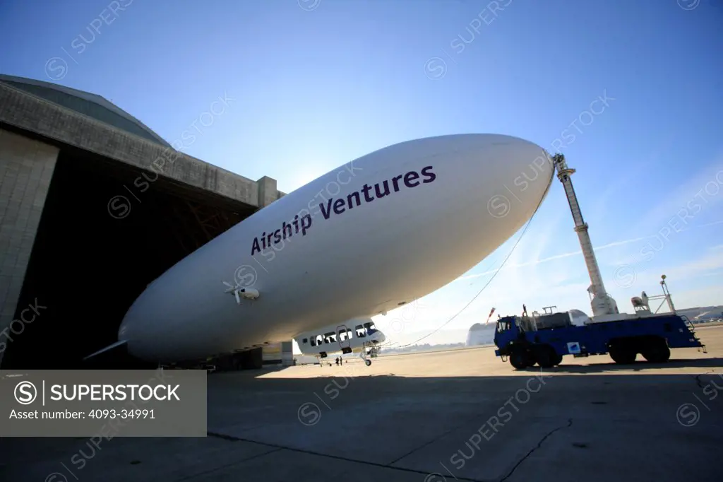 Front 3/4 view of the Zeppelin NT N704LZ Eureka being pulled out of the airship hanger at Moffett Federal Airfield in the Bay Area of Northern California. Attached to it's mooring dock truck.