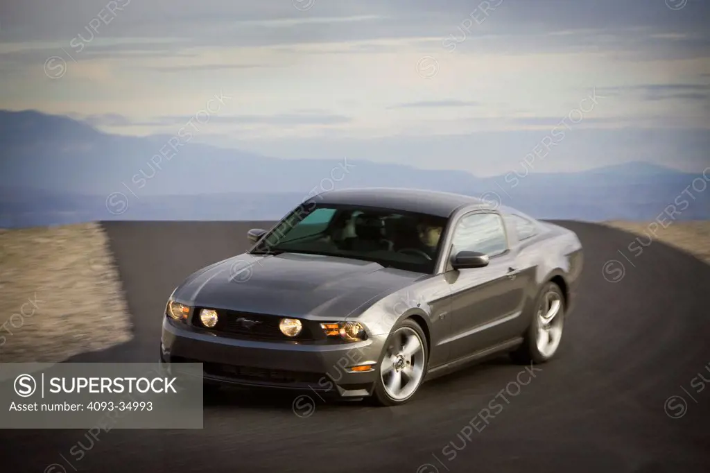 Front 3/4 action view of a gray 2010 Ford Mustang GT on a desert race track.