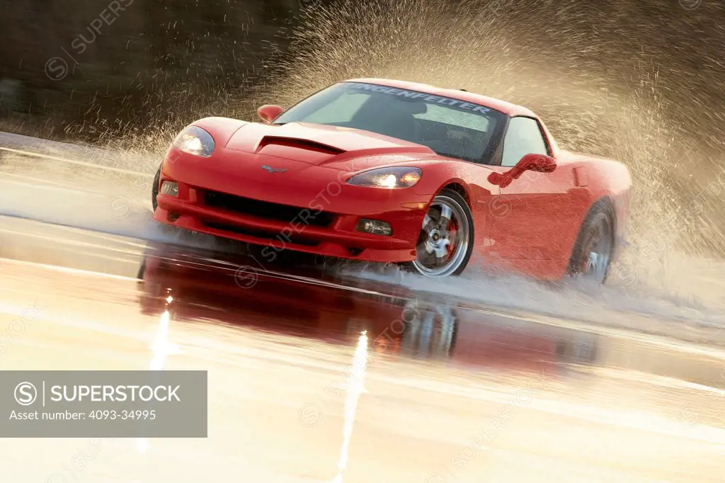 Front 3/4 action view of a red 2010 Lingenfelter Chevrolet Corvette in a four wheel drift on a wet skid pad.