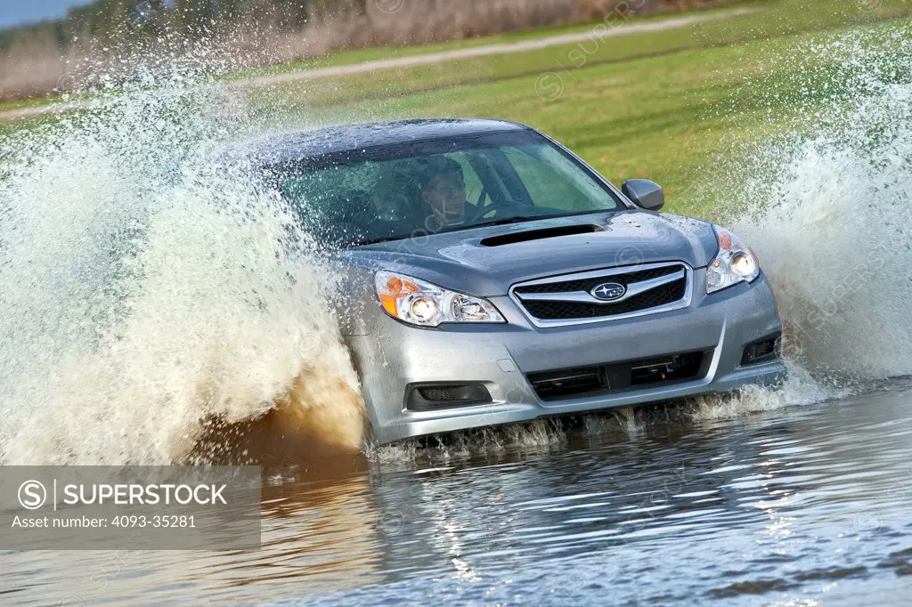 2010 Subaru Legacy 2.5 GT sedan driving through a stream filled with water. Water spray coming from vehicle, front 3/4 action view