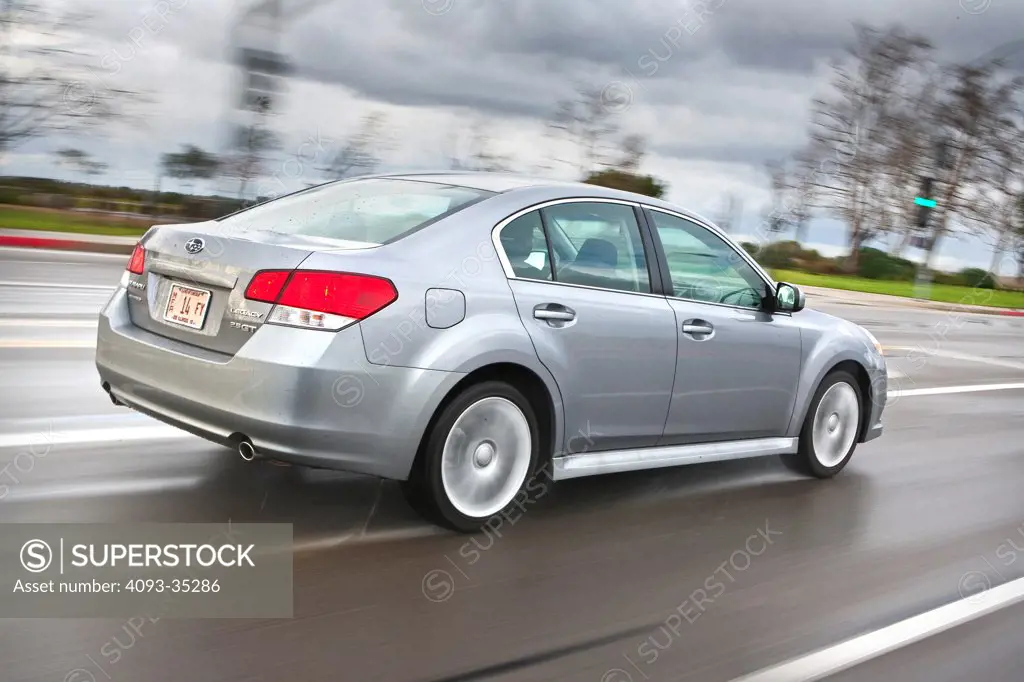 2010 Subaru Legacy 2.5 GT sedan driving in a suburban location, rear 3/4 action view