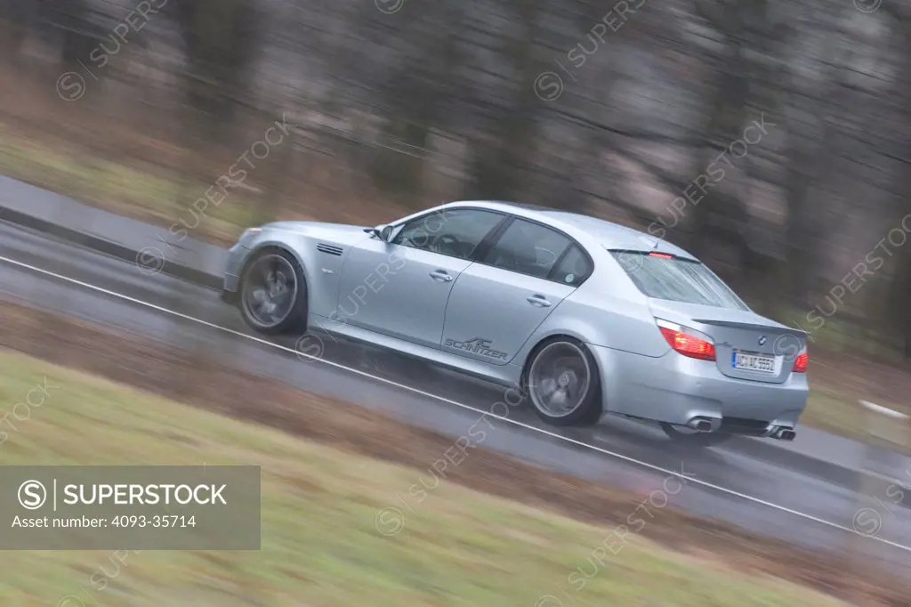 2006 AC Schnitzer ACS5 BMW M5 driving on a rural road in the rain, rear 3/4