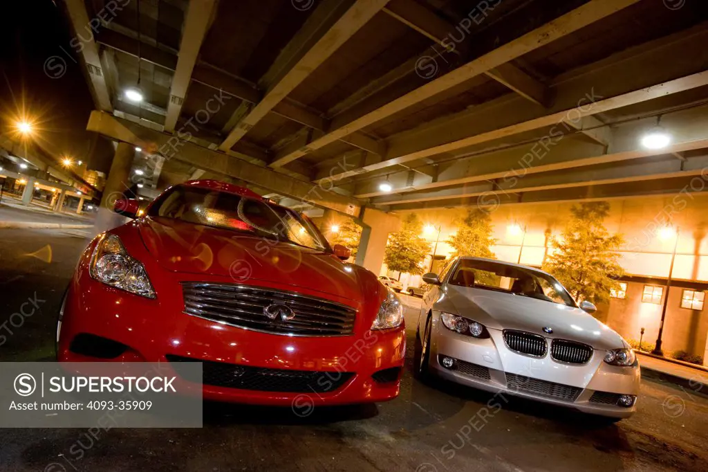 2007 BMW 335i Coupe and red 2008 Infiniti G37S parked under an overpass bridge at night