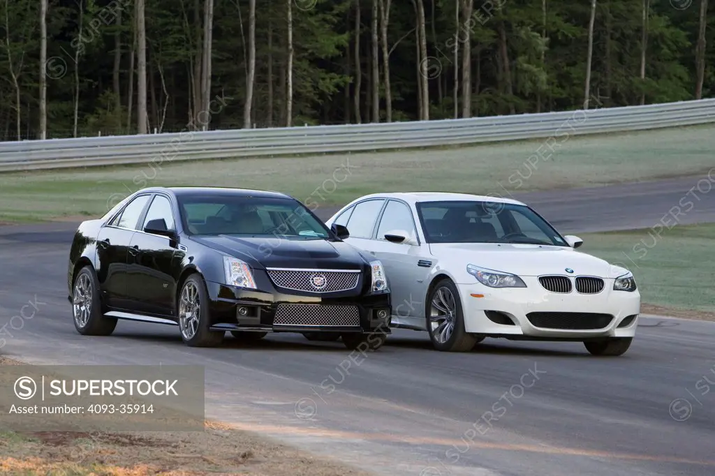 2009 Cadillac CTS-V and white 2008 BMW M5 on a race track, front 3/4