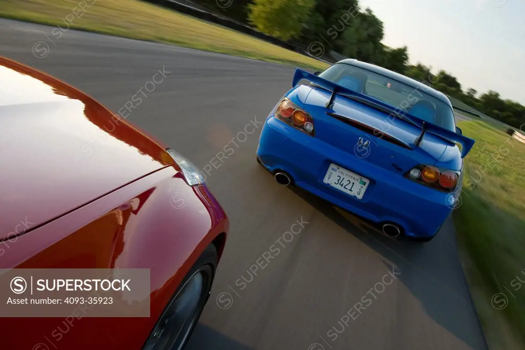 2008 Honda S2000 and red 2007 Nissan Nismo 350Z racing on a race track, rear view