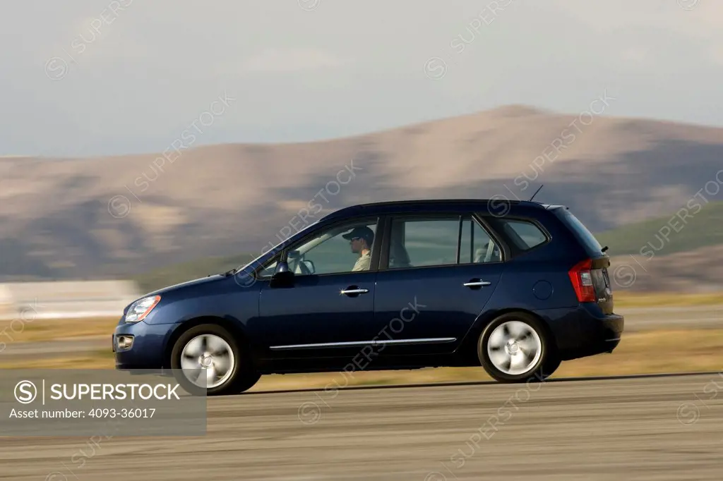2007 Kia Rondo EX V6 driving on a rural road, side view